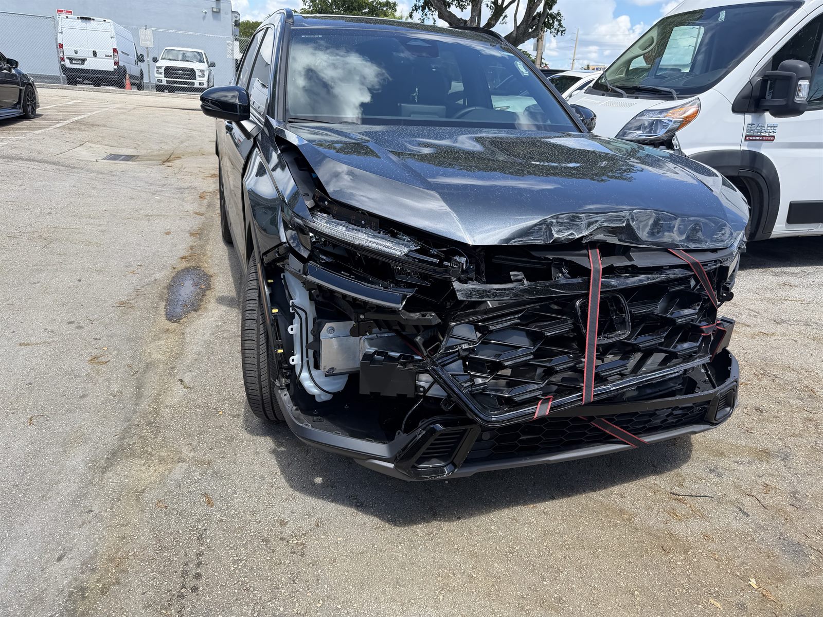 Honda CR-V front-end collision damage before repair — bumper off, grille strapped